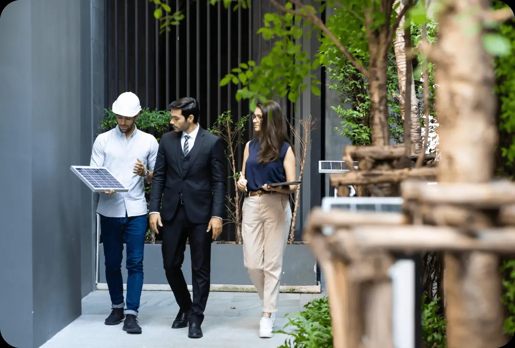 A trio of people walks on a sidewalk, discussing solar panels, highlighting the importance of renewable energy sources.